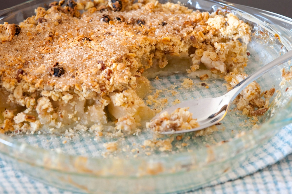 crumble de maçã, uma sobremesa de origem inglesa, disposta em uma travessa de vidro em cima de uma mesa