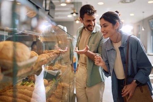 Casal olhando vitrine - mercado de bolos e salgados