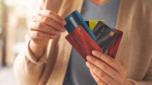 Mulher selecionando um cartão de crédito entre vários