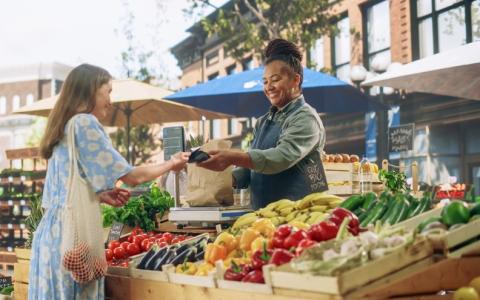 Feirantes - mulher vendendo verduras para cliente em feira