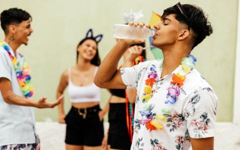 Folião tomando água de kit folia 