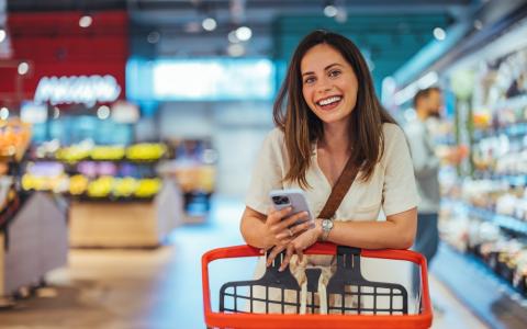 Mulher comprando no mercado e olhando no celular onde vê marketing emocional