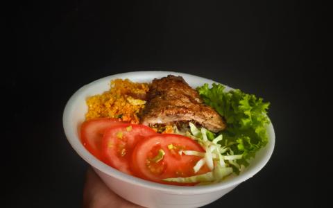 Marmitas fitness: mão segurando marmita cheia com fundo preto