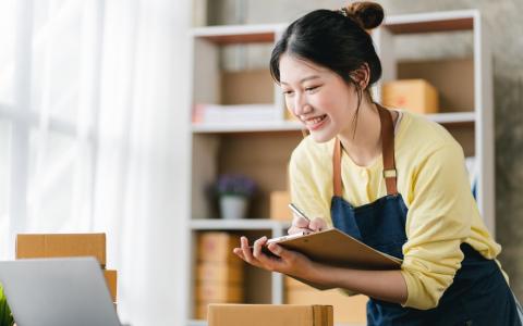 Mulher com caixas de encomendas e prancheta com prazo de entrega
