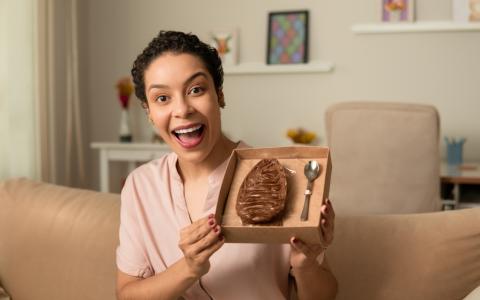Mulher segurando um ovo de Páscoa de colher embalado