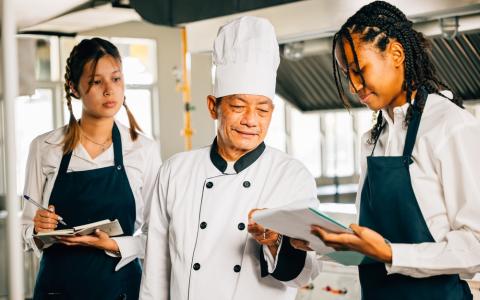 Chef realizando treinamento com duas garçonetes
